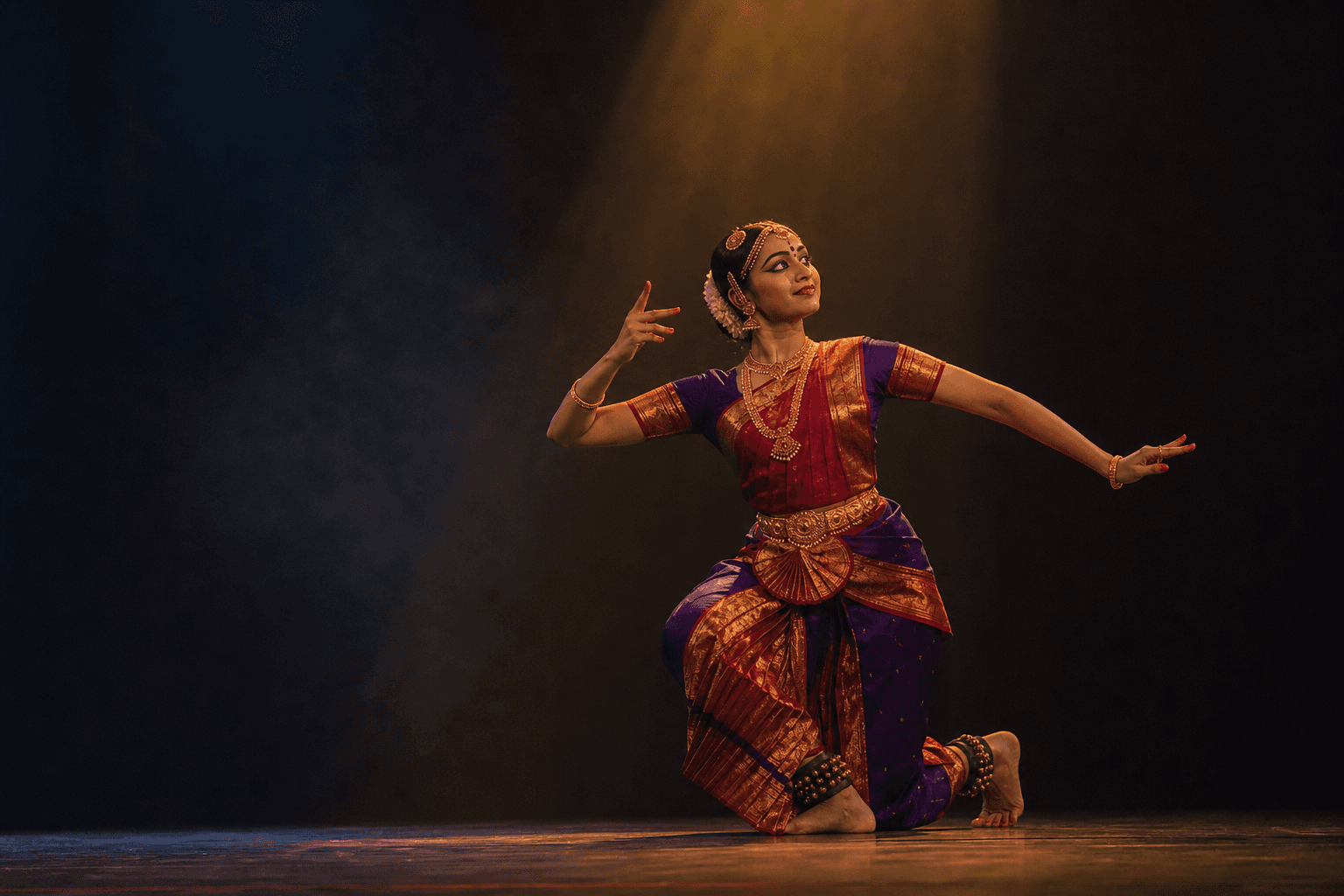 Bharatanatyam dancer performing under a warm theatre spotlight